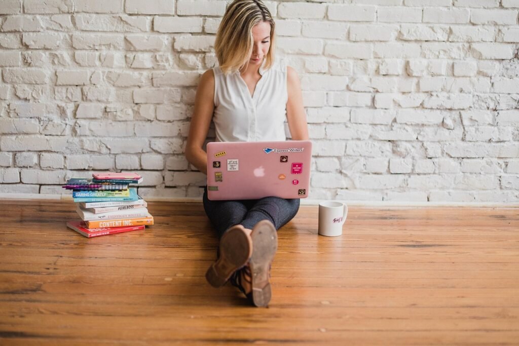 Criadora de conteúdo usando IA para criar conteúdo em um notebook, ao lado de microfone e câmera